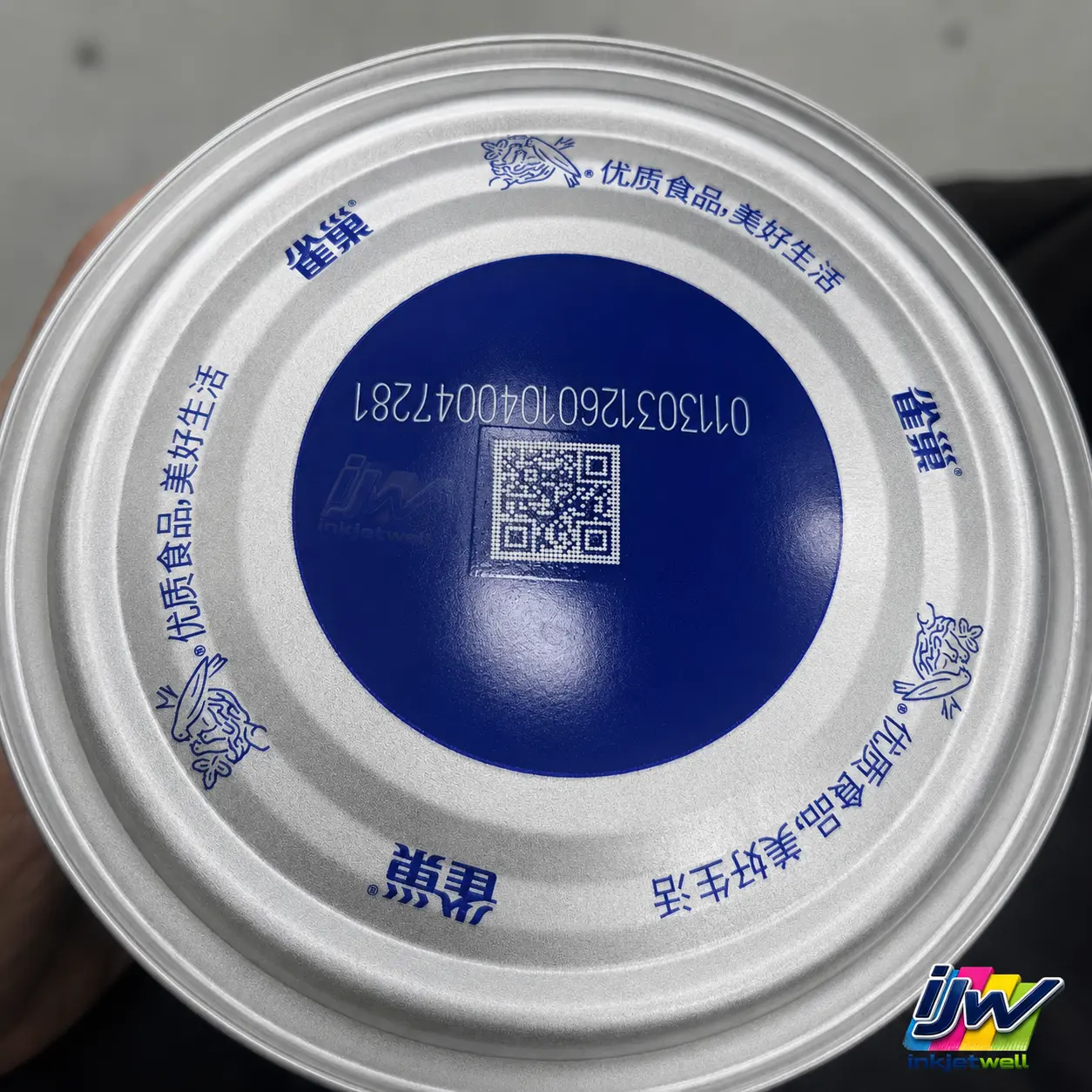 White QR code and numeric identifier printed over a dark coated metal-can lid